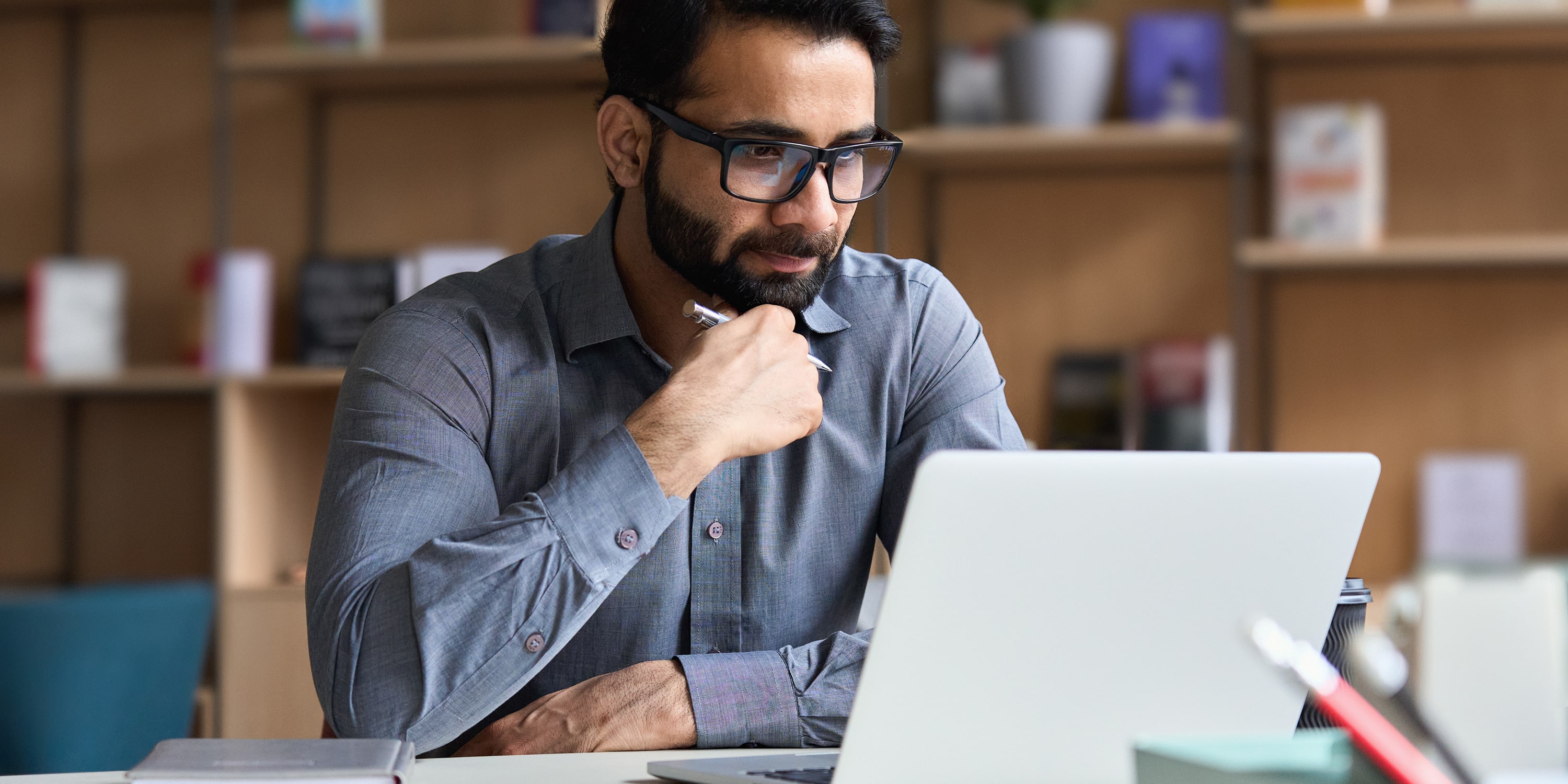 a man with glasses reading about business transformation on a laptop