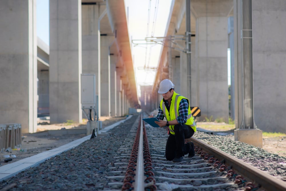 engineer kneeling to check railway track 