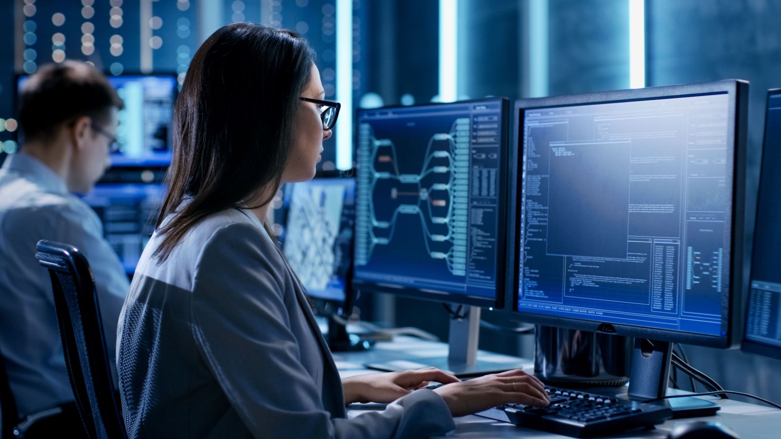 woman looking at two computer screens thinking about ai cybersecurity risks