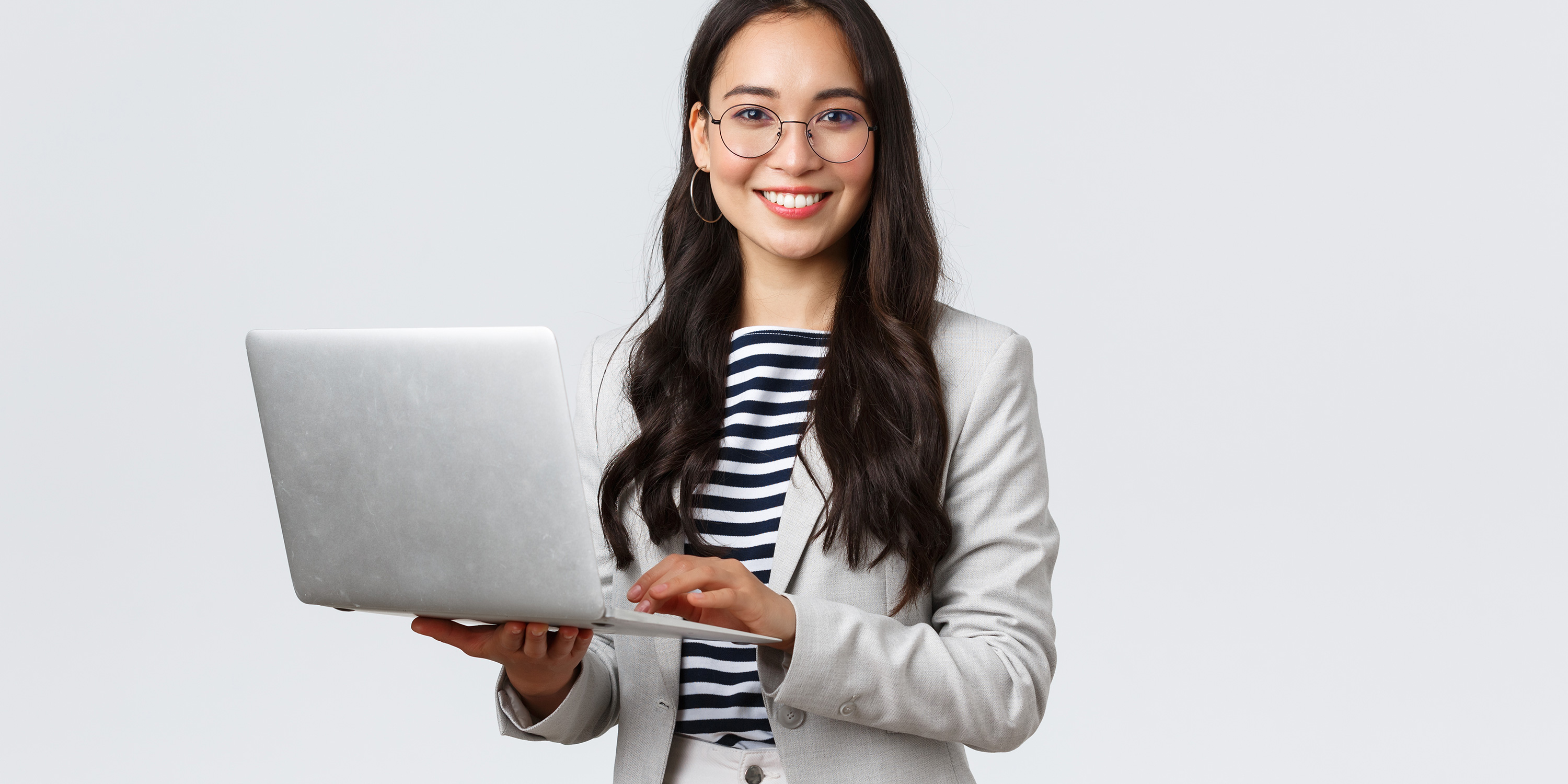 female with dark hair smiling and holding a laptop